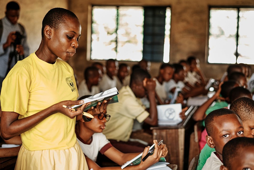 Port Harcourt, Rivers State, Nigeria - 23rd June 2021: A non-profit organization visits the Community Secondary School in Oginigba Community, Port Harcourt for an educational charity donation event. by Learning Game a woman standing in front of a group of children