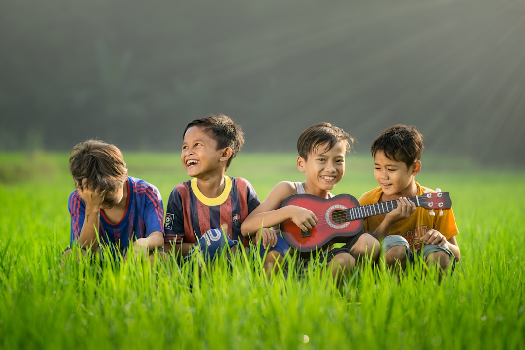 Jakarta shoot by Learning Game four boys laughing and sitting on grass during daytime